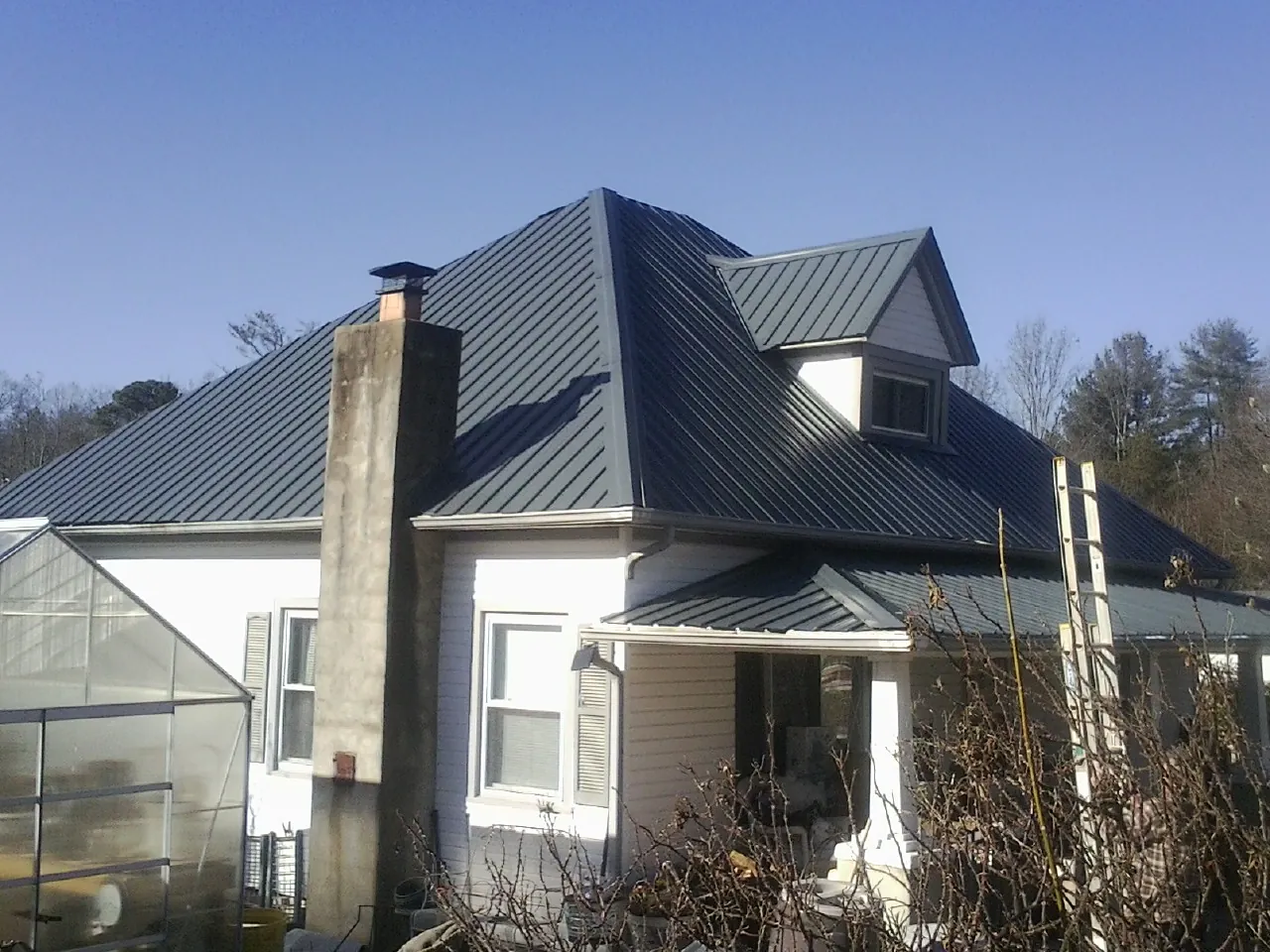 Dark blue standing seam metal roof on a white farmhouse with dormer — Slate & Tile Roof Repair by Roofing Brothers in Parksville