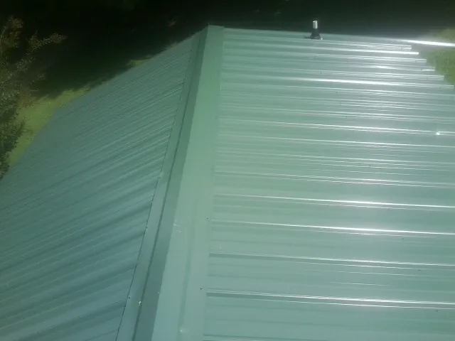 New green metal panels meeting at the ridge of a roof — Flat Roof Repair work by our crew in Parksville